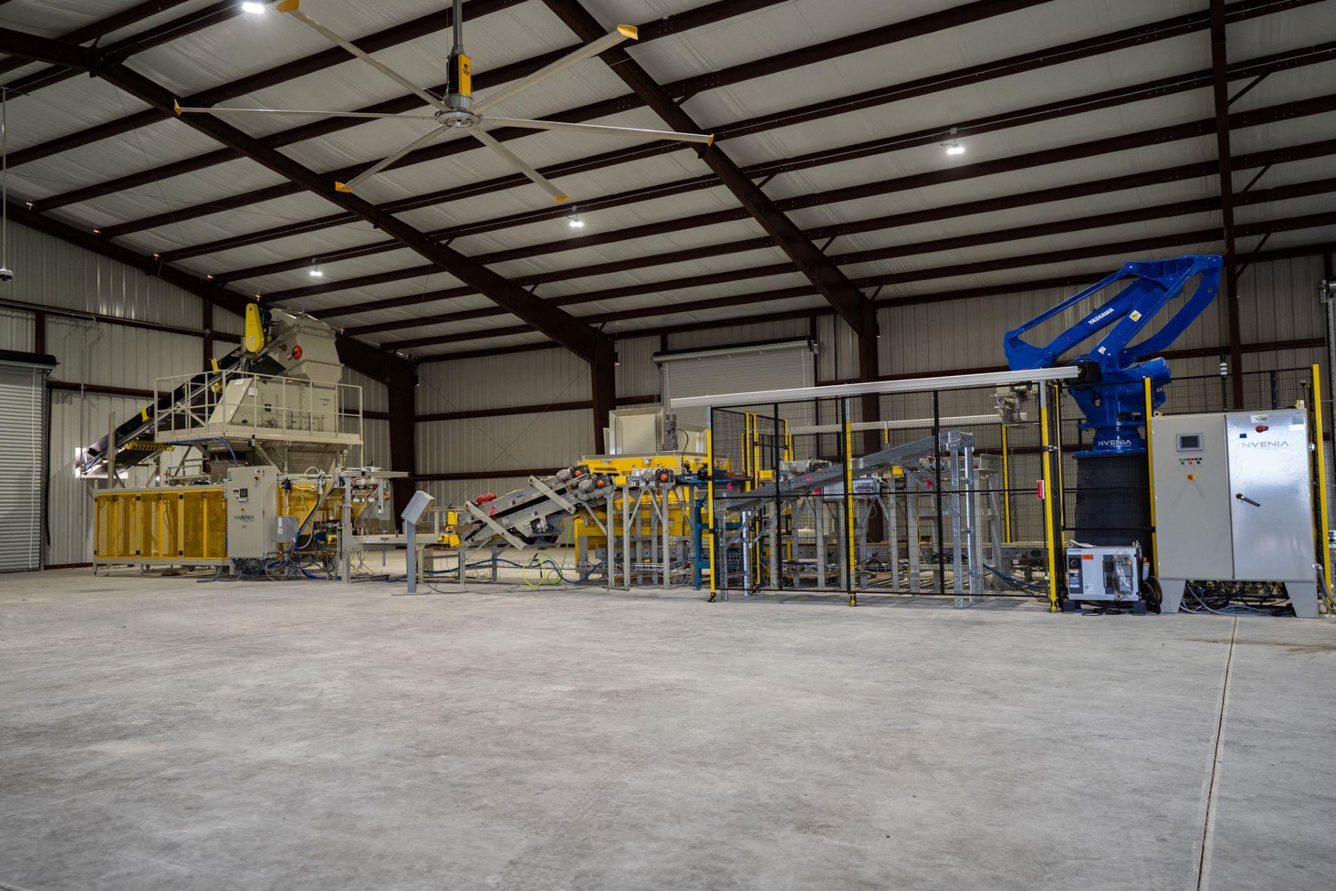 Industrial warehouse interior featuring automated machinery, conveyor belts, and metal equipment under a high ceiling with exposed beams—ideal for bulk organic soil Florida wholesale operations.